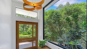 Ein modernes Interieur mit einem großen Fenster, einer Holztür und einer Pflanze auf einer Holzkonsole.