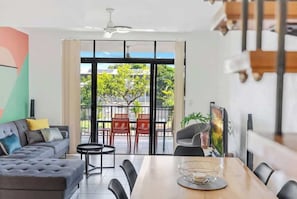 Un soggiorno moderno con divano, tavolo da pranzo, sedie e un balcone con sedie rosse.