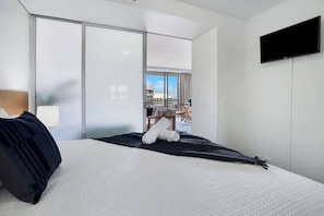 Una camera d'albergo con un letto, una televisione, una porta scorrevole e vista sull'esterno.