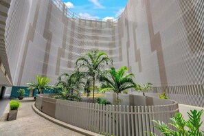A modern atrium with a curved walkway, vertical architectural lines, and potted plants.