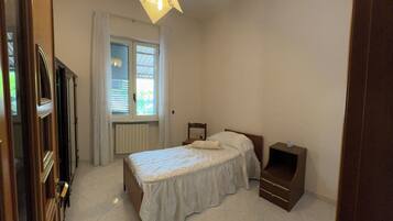 Una camera da letto con un letto, un comodino, una finestra con tende e una porta.