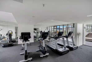 A modern gym with treadmills, elliptical machines, and weight equipment.