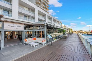 A waterfront dining area with outdoor seating, a sign for 'Waterfront Dining,' and a view of the water.
