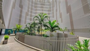 A modern atrium with a curved walkway, vertical architectural lines, and potted plants. - City Living at Harbour Lights on the Waterfront (Cairns)