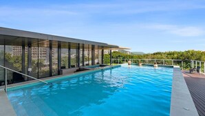 Une piscine au design moderne, entourée d’un espace abrité avec des murs en verre.