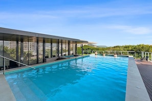 Una piscina dal design moderno, circondata da un'area coperta con pareti in vetro.