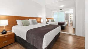 Une chambre d’hôtel avec un grand lit, une table de chevet, un miroir et une vue sur la ville par la fenêtre.