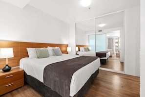 Camera d'albergo con un letto grande, un comodino, uno specchio e vista sulla città dalla finestra.