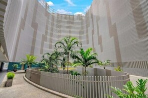 Un atrium moderne avec une balustrade incurvée, des palmiers et un plafond haut.