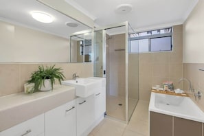 Un bagno moderno con box doccia in vetro, lavabo doppio e una pianta in vaso.