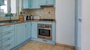 Une cuisine de taille réduite avec des meubles de couleur bleu clair, une cuisinière à gaz, un four et un évier.