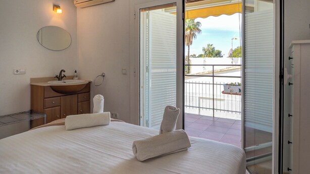 Une chambre d’hôtel avec un lit, une salle de bain avec un lavabo et une vue sur le balcon extérieur.