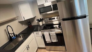 A modern kitchen with stainless steel appliances, white cabinets, and a black countertop.
