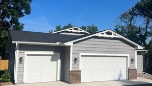 A two-story house with a garage, a covered patio, and a well-maintained lawn.