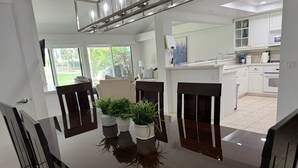 A modern dining area with a glossy black table, dark chairs, and potted plants. - Beautiful and charming condo in Woodhaven Country Club! Recently updated (Palm Desert)