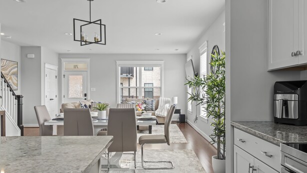 Een moderne keuken met granieten aanrechtbladen, roestvrijstalen apparatuur en een eethoek met een marmeren eiland en moderne stoelen.