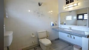 Een badkamer met toilet, wastafel en spiegel.
