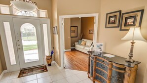 A hallway with a white door, a wooden bench with drawers, and framed pictures on the wall.