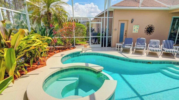 A swimming pool with a curved design, surrounded by lounge chairs and tropical plants.