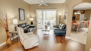 A spacious living room with a fireplace, a dining area with a table and chairs, and a kitchen visible through an archway.