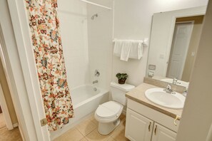A bathroom with a shower, toilet, sink, and a mirror.