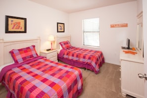 A bedroom with two beds, a nightstand, a lamp, a dresser, and a window with blinds. - Robert's Cypress Pointe Vacation Home (Davenport)