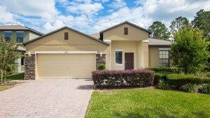 A two-story house with a beige garage door, a stone facade, and a well-maintained lawn. - Robert's Cypress Pointe Vacation Home (Davenport)