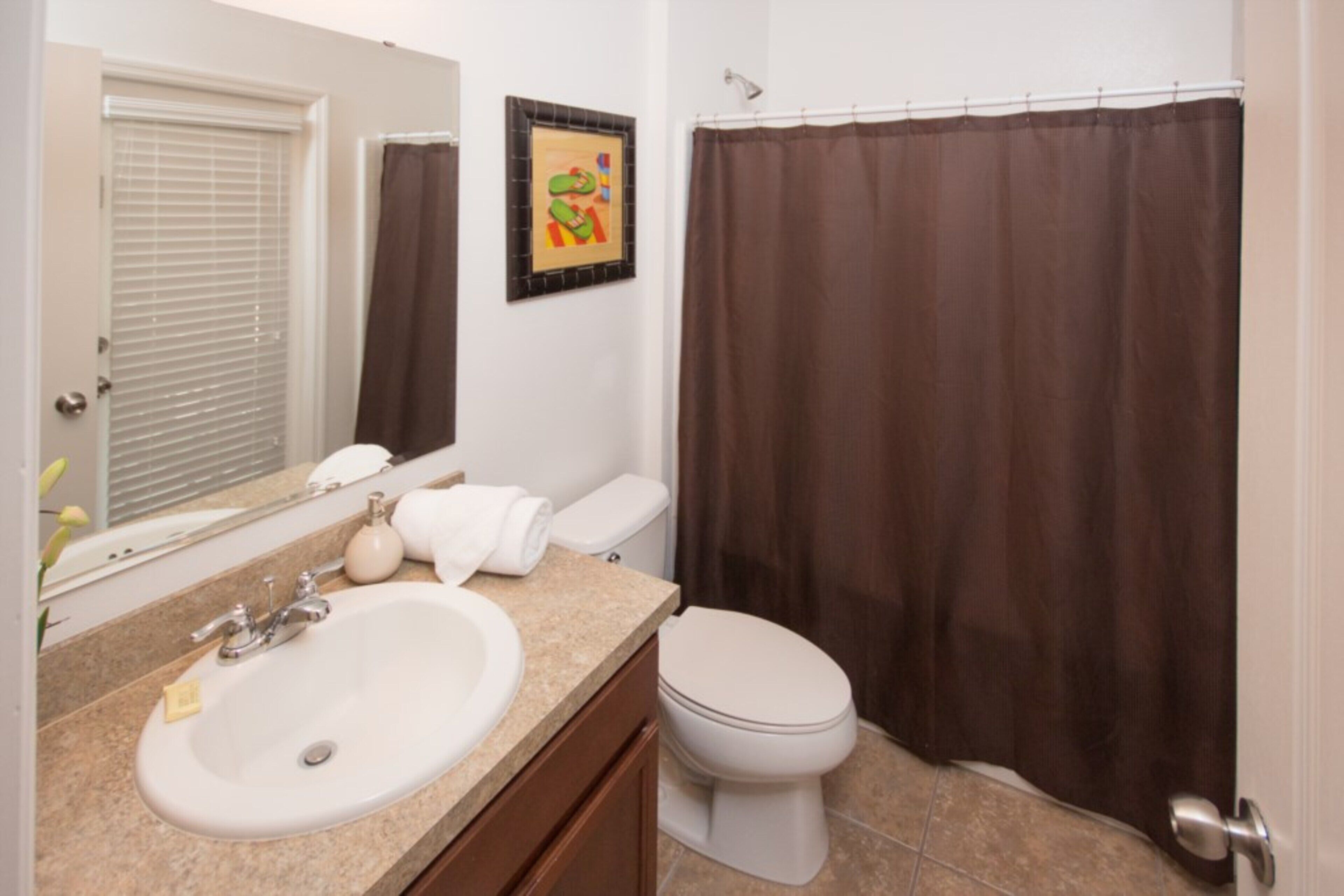 A bathroom with a sink, toilet, and shower curtain.