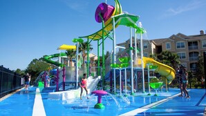 A water park with multiple slides and water features, surrounded by a pool and a fence.