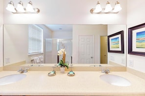A bathroom with two sinks, a large mirror, and a potted orchid. - TIm and Helen's West Haven Vacation Home (Davenport)