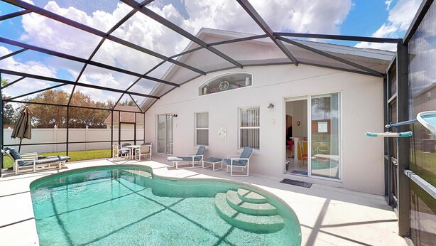 A covered outdoor swimming pool with lounge chairs and a glass door entrance. - Len & Arlene's Tuscan Ridge Vacation Home (Davenport)