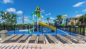 Parque acuático con toboganes y piscina, rodeado por una valla y tumbonas.