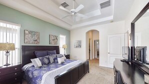 A bedroom with a large bed, a ceiling fan, and artwork on the walls. - Jagjit's Tuscan Hills Vacation Home (Davenport)