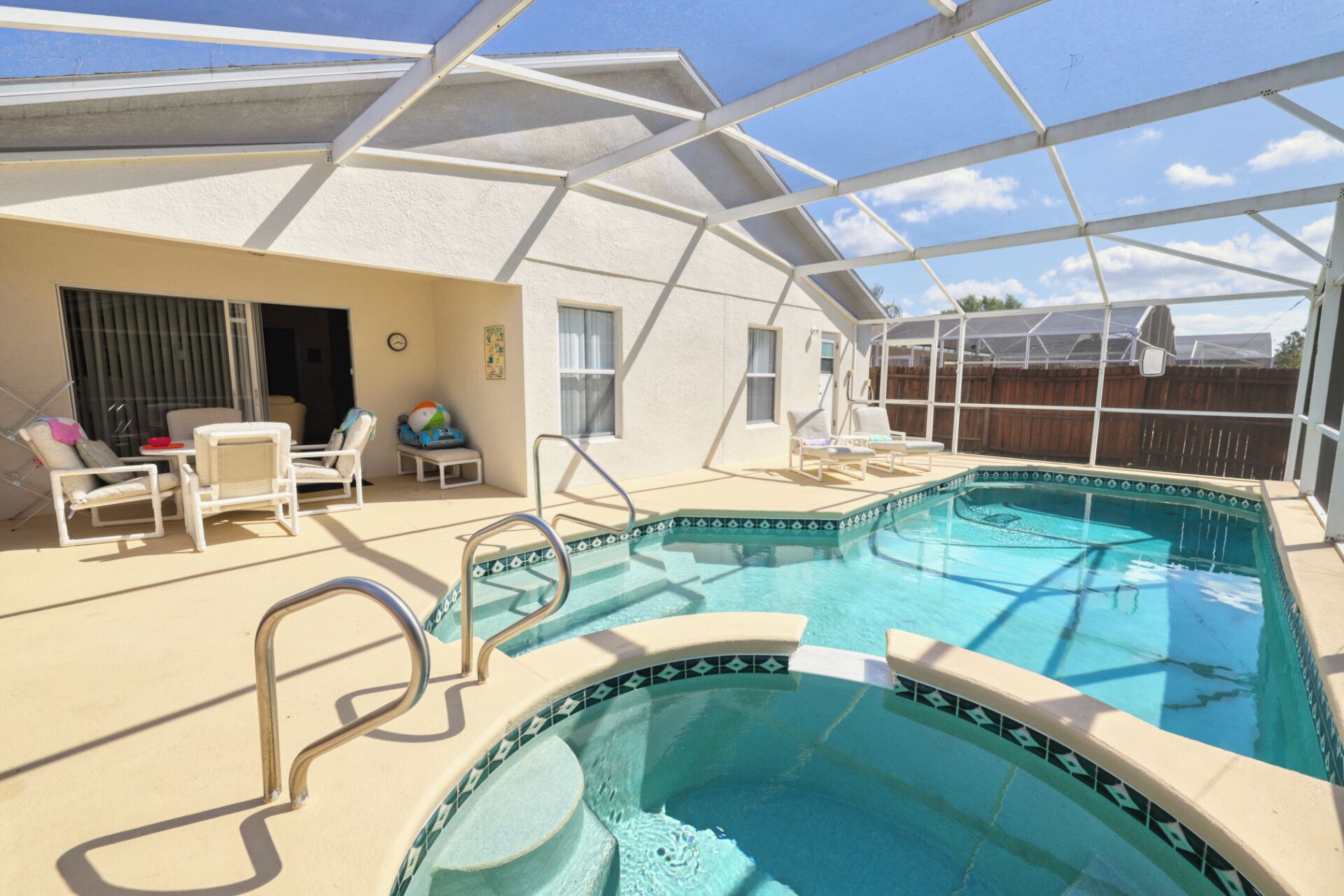 A swimming pool with a covered patio area, including lounge chairs and a small table.