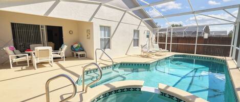 A swimming pool with a covered patio area, including lounge chairs and a small table.