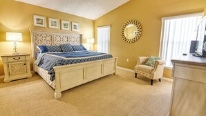 Une chambre à coucher avec un grand lit, une table de chevet, une chaise, un miroir et une fenêtre avec des stores.