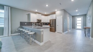 Cozinha moderna com ilha central, banquetas e eletrodomésticos de aço inoxidável.