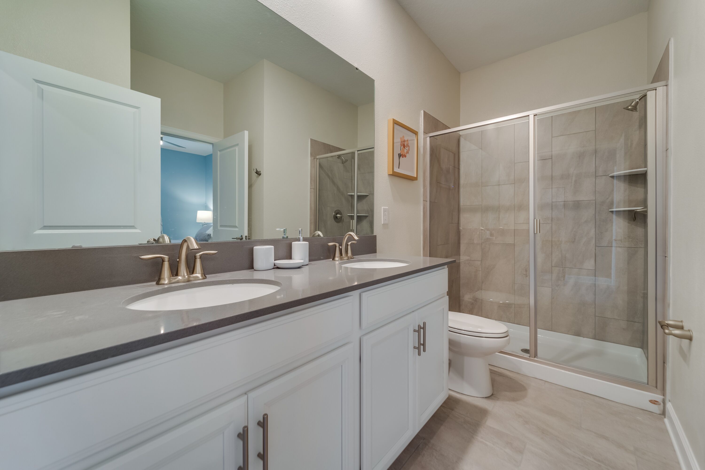 Een moderne badkamer met twee wasbakken, een toilet en een douchecabine met glazen wanden.