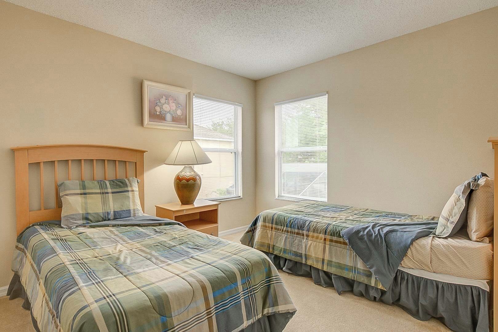 A bedroom with two beds, a nightstand with a lamp, and a framed picture on the wall.