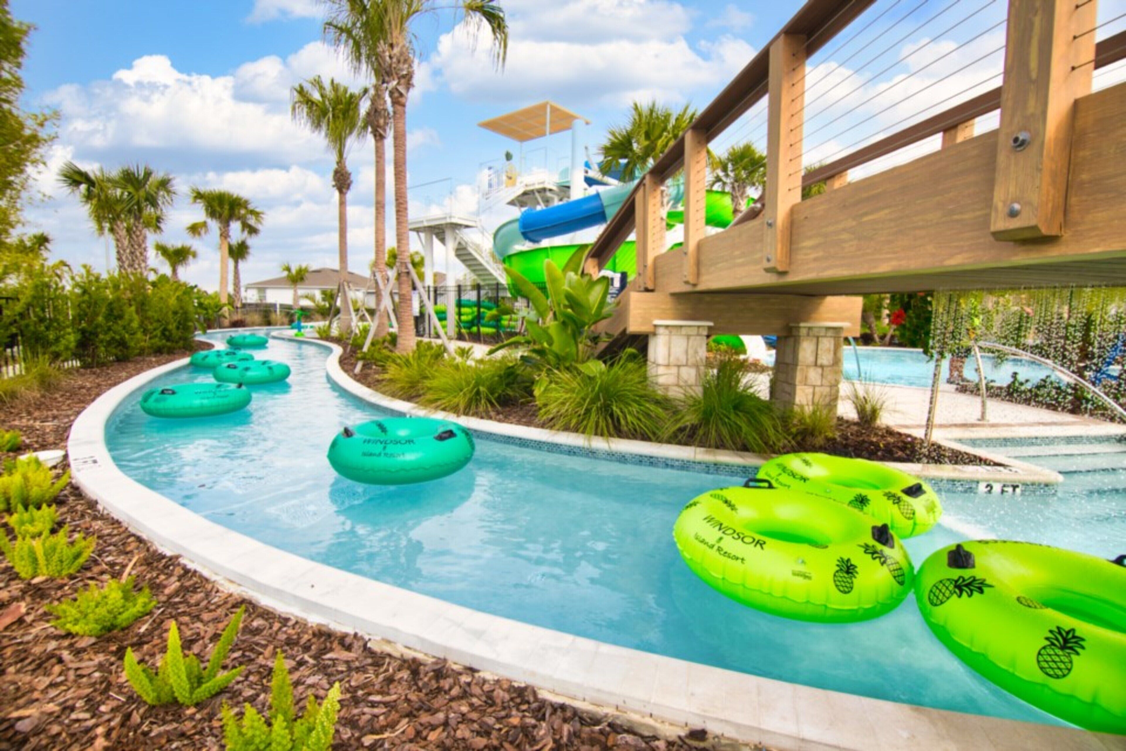 Ein Wasserpark mit Pool, Schwimmreifen, Palmen und einer Rutsche.