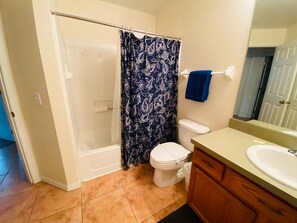 A bathroom with a shower, toilet, sink, and vanity.