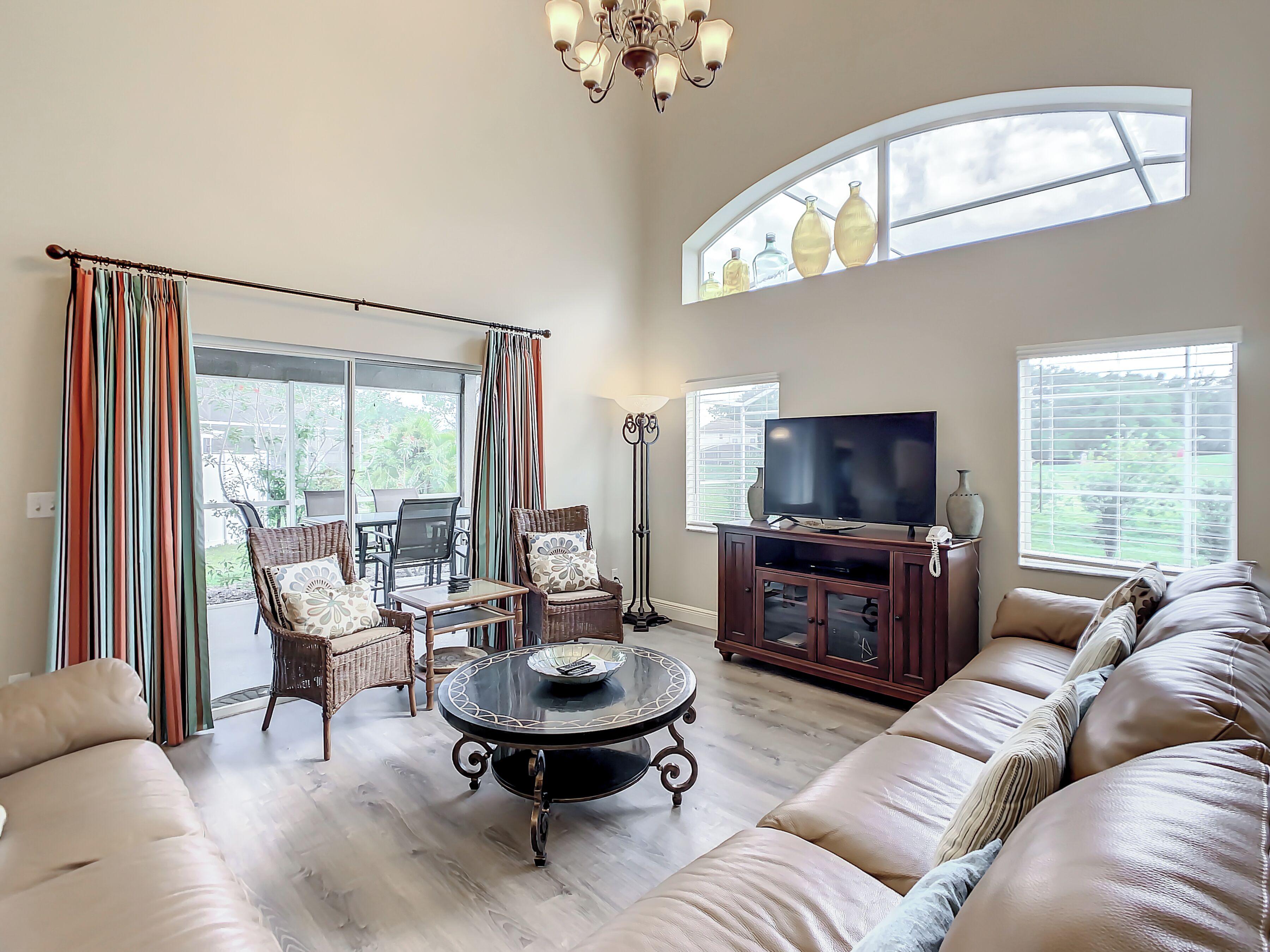 A spacious living room with a large sofa, a dining table, and a television.