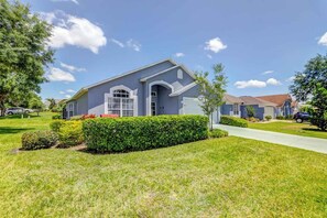 A two-story residential house with a front yard, driveway, and neighboring houses.