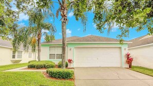 A single-story house with a garage, surrounded by well-maintained lawns and palm trees. - Southern Dunes Vacation Home (Haines City)