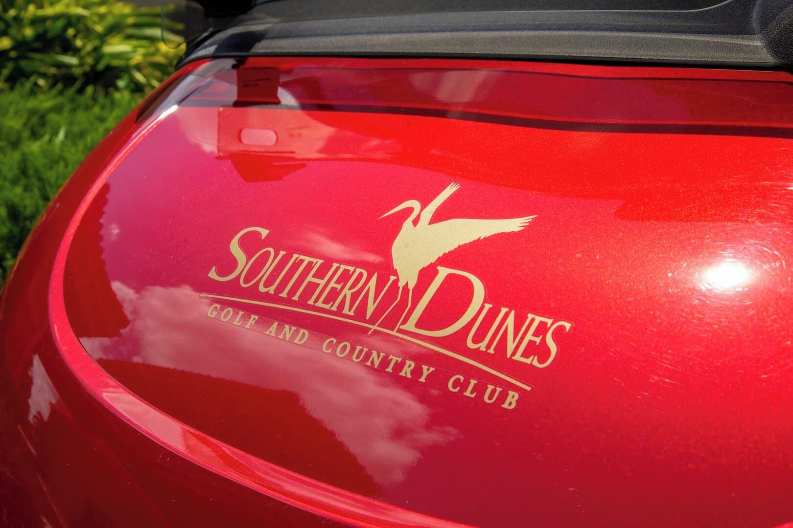 A red car with a logo and text reading "Southern Dunes Golf and Country Club" on its rear.