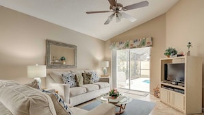 A living room with a sofa, coffee table, TV stand, and a ceiling fan. - Southern Dunes Vacation Home (Haines City)