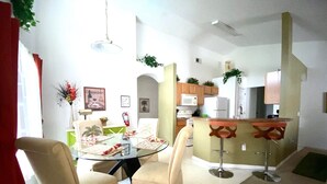 A compact living space with a dining area, kitchen, and a small bar area.