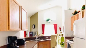 A kitchen with wooden cabinets, a coffee maker, a sink, and a refrigerator.