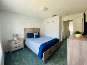 Ein Schlafzimmer mit Bett, Nachttisch, Lampe und Kommode.