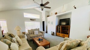 Un salon comprenant un canapé, une table basse, un téléviseur et un ventilateur de plafond.